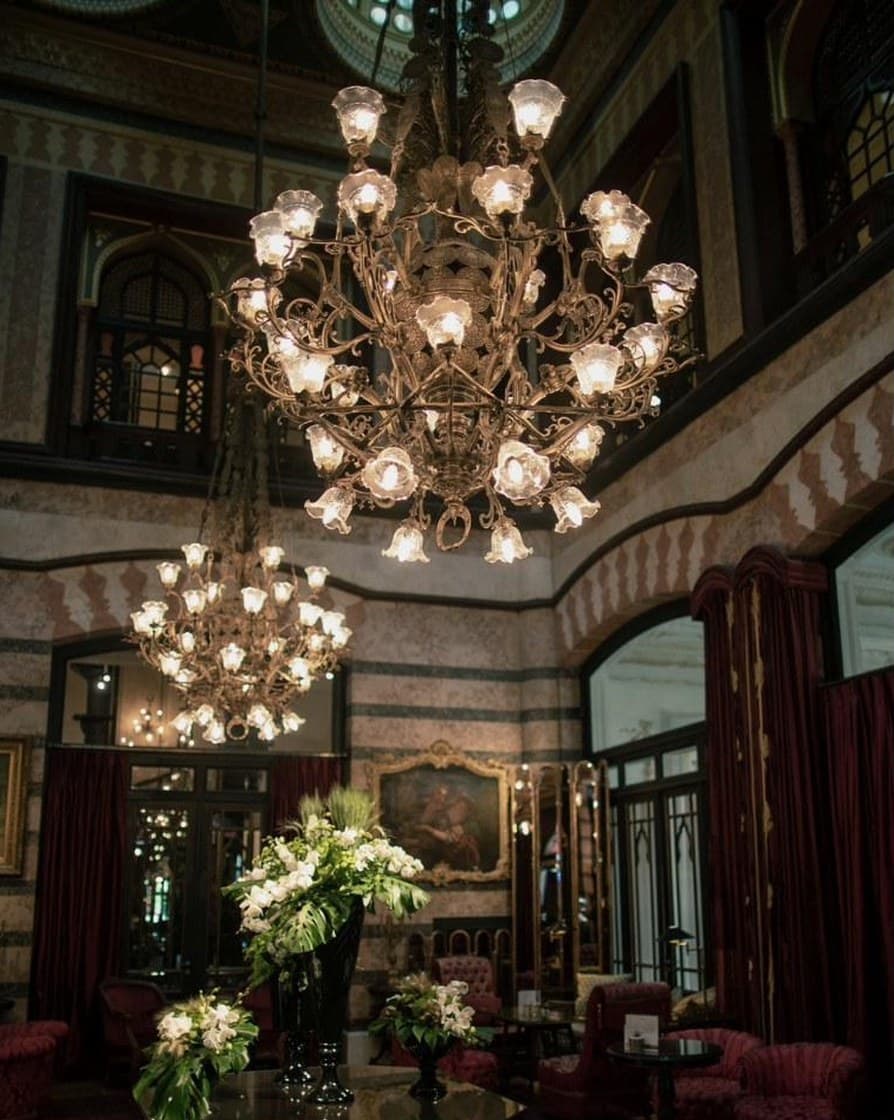 Salon d'hôtel aux lustres anciens, fauteuils de velours et lumière tamisée