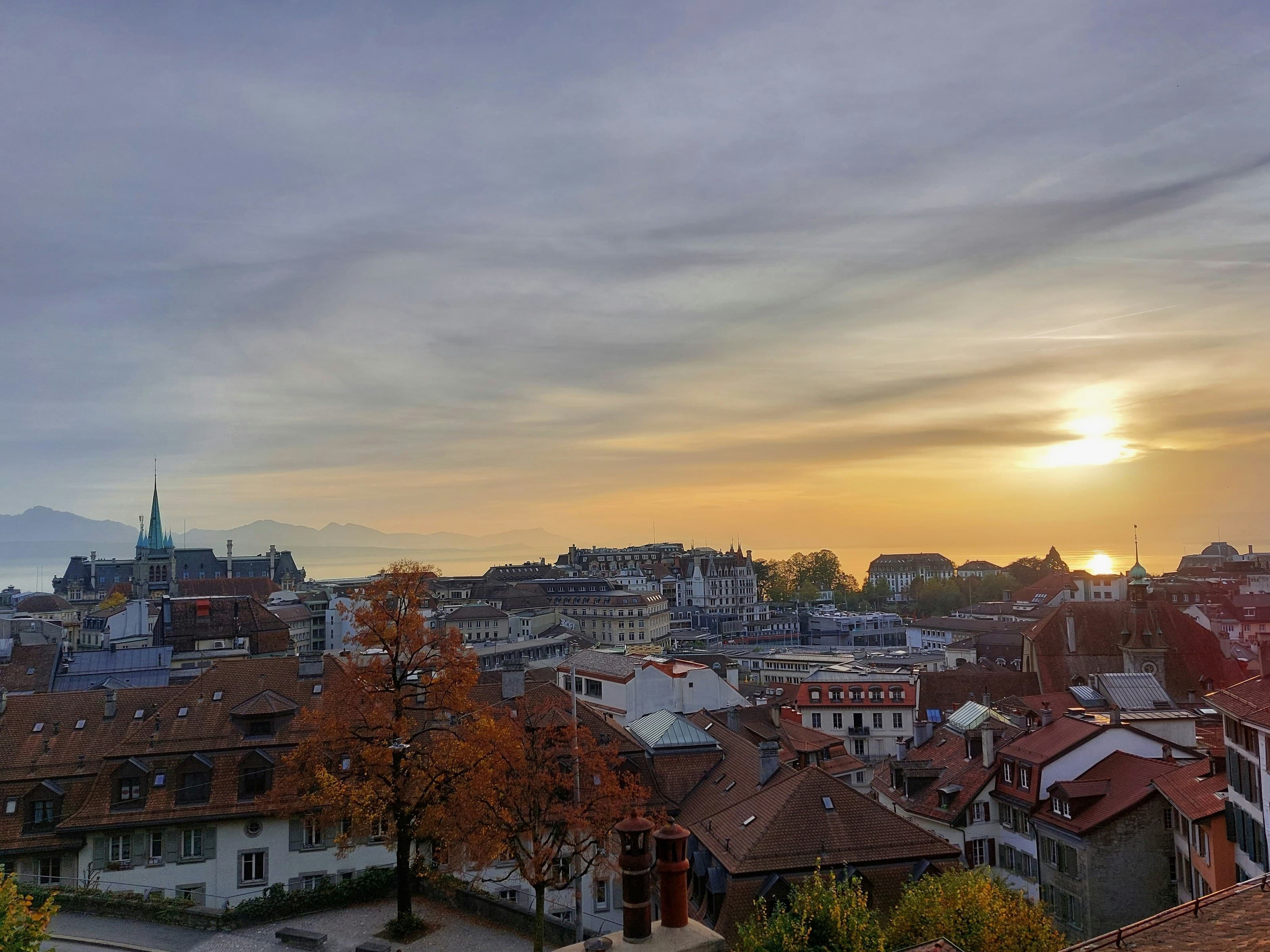 Les toits de Lausanne et la cathédrale au soleil couchant, le Léman et les Alpes au fond
